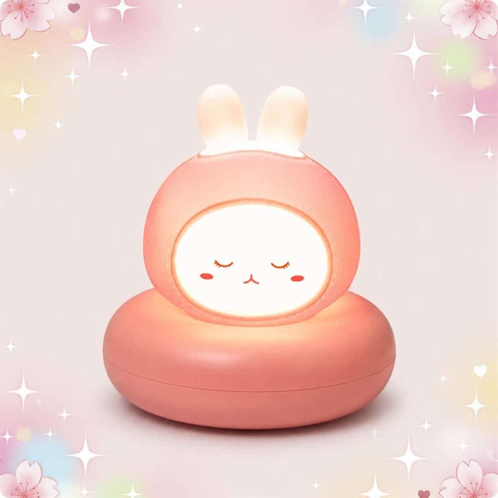 Une veilleuse Kawaii en lapin avec réglage tactile progressif rose, en forme de petit lapin lumineux, posée sur fond pastel avec des étoiles et des cœurs.