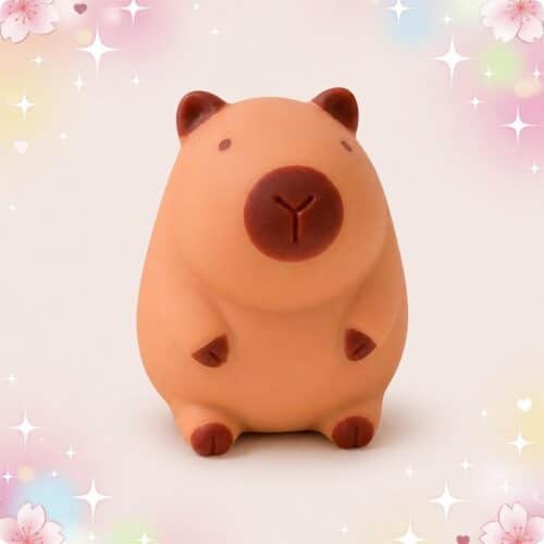 Un Anti-stress squishy Capybara en forme de petit capybara brun à presser, posé sur un fond pastel avec des étoiles et des fleurs.