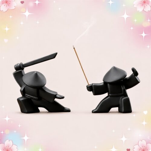 Deux figurines noires de samouraï pour décoration japonaise 2 brûleurs d'encens samouraï, l’une brandissant un sabre et l’autre tenant un bâton d’encens, sur fond rose doux.