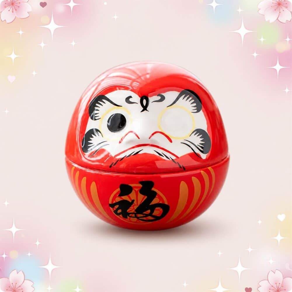 Une décoration japonaise Daruma porte bonheur rouge, ronde et souriante, posée sur un fond doux et décoré de petites fleurs et d’étoiles brillantes.