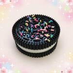 Un jouet anti-stress squishy Oreo kawaii en forme de biscuit noir, avec une crème blanche au milieu et des petites décorations colorées, sur un fond rose doux et brillant.