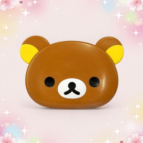Un miroir kawaii Rilakkuma pliable avec peigne marron et jaune, en forme de tête d’ours, posé sur un fond rose doux et brillant.