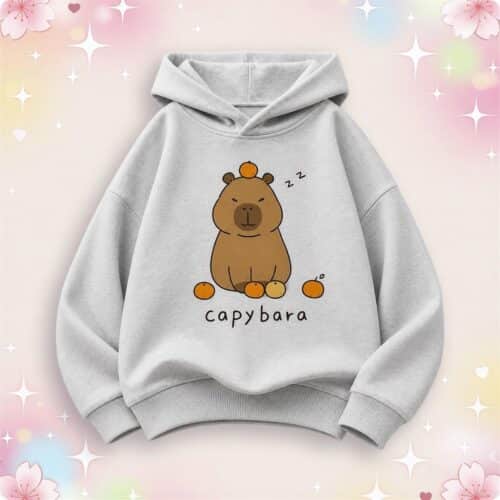 Un pull kawaii capybara pour enfant gris clair avec un dessin de capybara endormie, sur un fond pastel décoré d’étoiles et de petits cœurs.