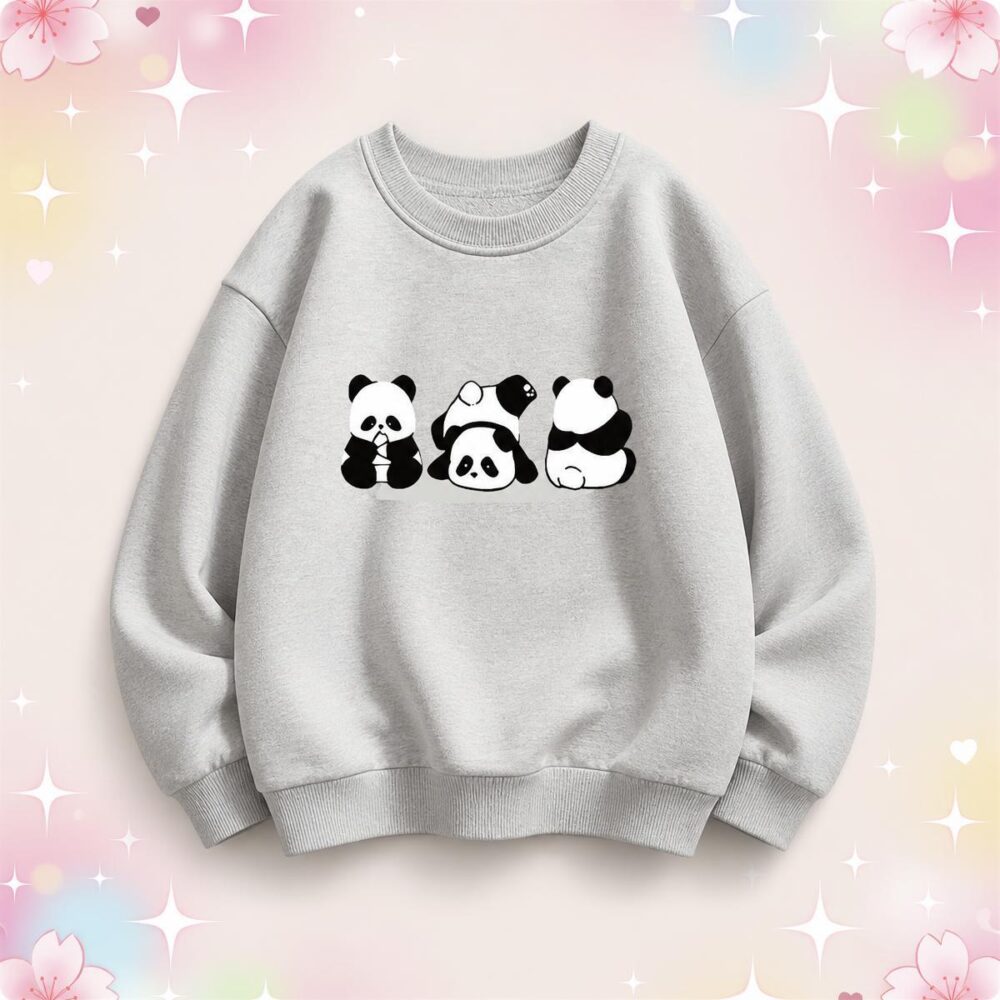 Un pull kawaii pour enfant à imprimé pandas gris clair avec trois petits pandas noirs et blancs au centre, sur fond doux rose et pastel.
