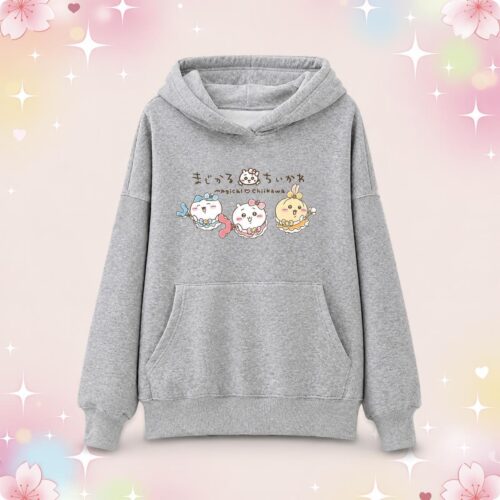 Un pull kawaii Magical Chiikawa gris à capuche avec poche kangourou, décoré de petits personnages mignons, posé sur un fond rose pastel avec des étoiles brillantes.