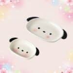 Deux petites assiettes de vaisselle kawaii assiette chiot mignon en forme de visage de chiot, avec des oreilles noires et des joues roses, sur un fond pastel rempli d’étoiles et de fleurs.