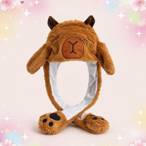 Un bonnet kawaii capybara marron aux oreilles mobiles en peluche, avec des oreilles d’animaux et des pattes au bout des liens, posé sur un fond rose doux et brillant.