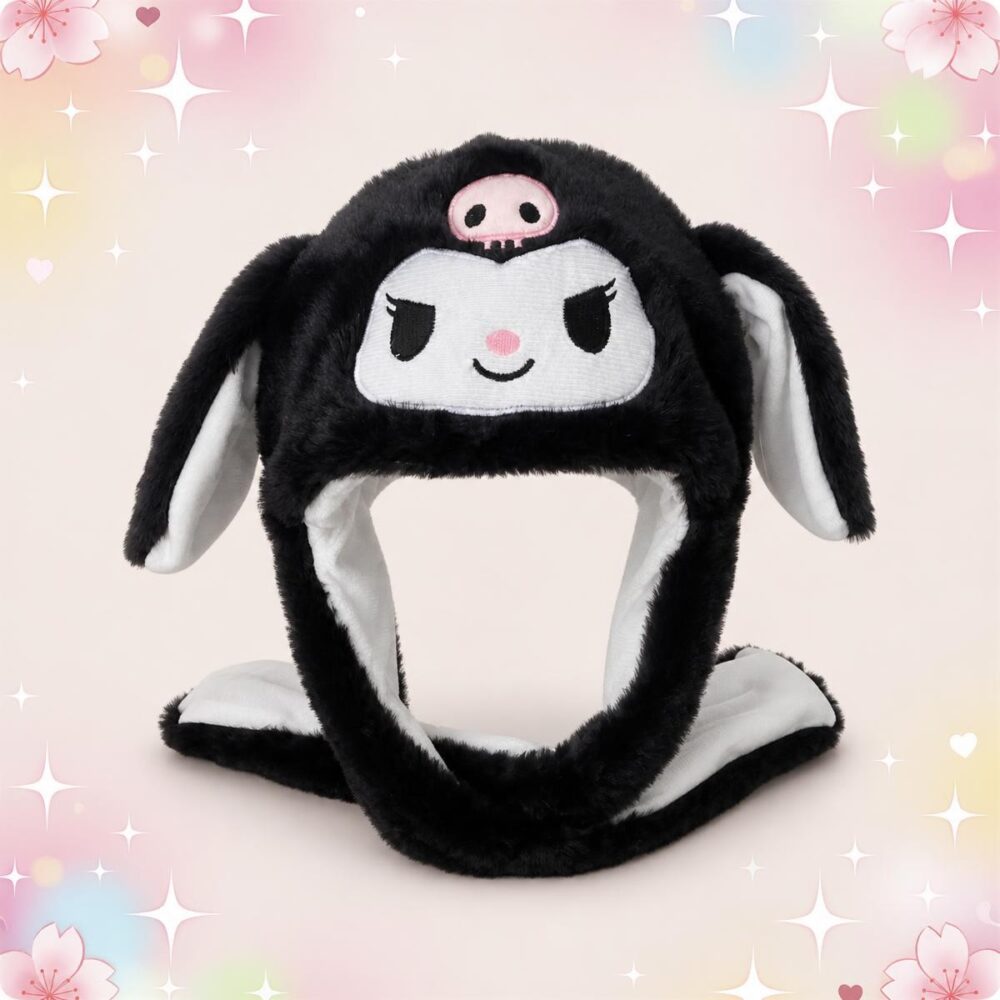 Un bonnet Kawaii Kuromi noir en peluche au crâne rose, avec de longues oreilles tombantes, posé sur un fond rose tendre et décoré d’étoiles et de petits cœurs.
