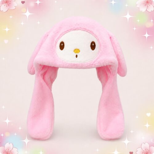 Un bonnet kawaii My Melody rose en peluche à oreilles, tout doux et tombant de chaque côté du visage, sur un fond pastel décoré d’étoiles et de fleurs.