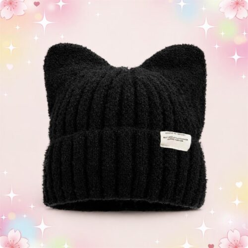 Un bonnet kawaii à oreilles de chat noir tricoté, doux et chaud, posé sur un fond rose décoré d’étoiles et de petits cœurs.