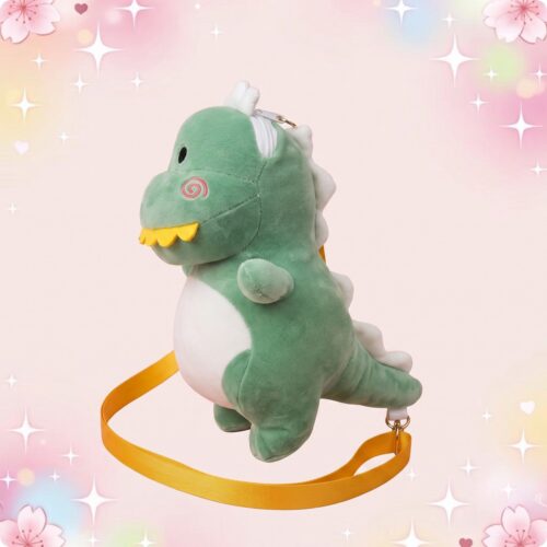 Un sac à main peluche dinosaure kawaii vert, avec ventre blanc, petites dents jaunes et longue bandoulière jaune, posé sur un fond rose doux avec des étoiles.