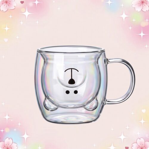 Une tasse kawaii à café ourson avec anse en verre transparent, avec un petit visage d’ourson sur le devant, posée sur un fond rose pastel décoré d’étoiles et de fleurs.