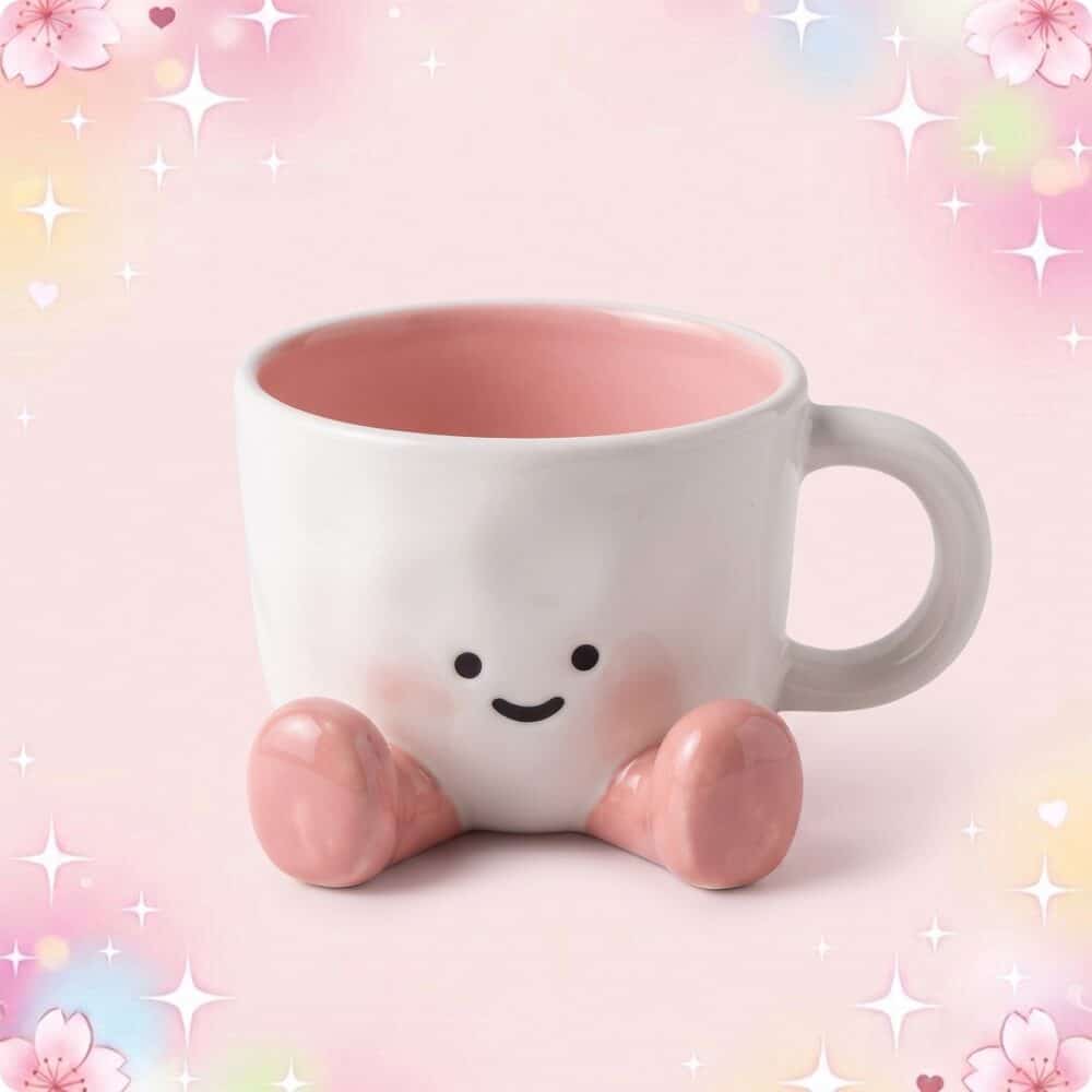 Une tasse kawaii à personnage mignon blanche et rose, avec un petit visage souriant et des pieds roses, posée sur un fond pastel décoré d’étoiles et de fleurs.
