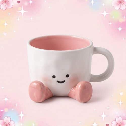 Une tasse kawaii à personnage mignon blanche et rose, avec un petit visage souriant et des pieds roses, posée sur un fond pastel décoré d’étoiles et de fleurs.