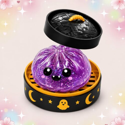 Un Mochi Squishy Halloween fantôme violet pailleté à petits crocs, posé dans une boîte noire et orange décorée de lunes et de petits fantômes.