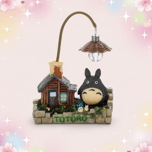 Une déco kawaii petite lampe Totoro avec Totoro, sa petite maison et une lampe suspendue, sur fond rose pastel décoré d’étoiles et de fleurs.
