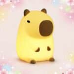 Une déco kawaii lampe veilleuse capybara en forme de petit capybara jaune, avec une lumière douce, sur un fond pastel décoré d’étoiles et de cœurs.