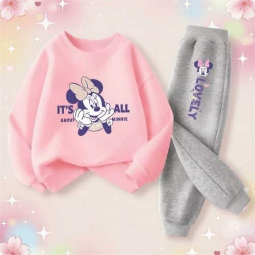 Un ensemble survêtement kawaii Minnie avec un sweat rose et un pantalon gris, posé sur un fond pastel décoré de petites étoiles et de cœurs.