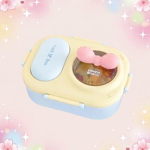 Une lunchbox kawaii à coloris pastel et noeud rose, avec couvercle bleu et jaune, posée sur un fond rose doux et lumineux.