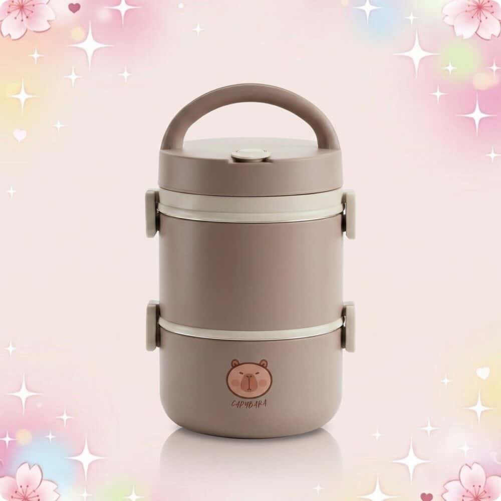 Une lunchbox kawaii thermique en acier inoxydable beige à deux compartiments, avec poignée et dessin de capybara, sur fond rose pastel avec fleurs et étoiles.