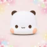 Un mochi squishy Bubu panda joufflu blanc avec des oreilles brunes et des joues roses, présenté sur un fond pastel décoré de fleurs et d’étoiles.
