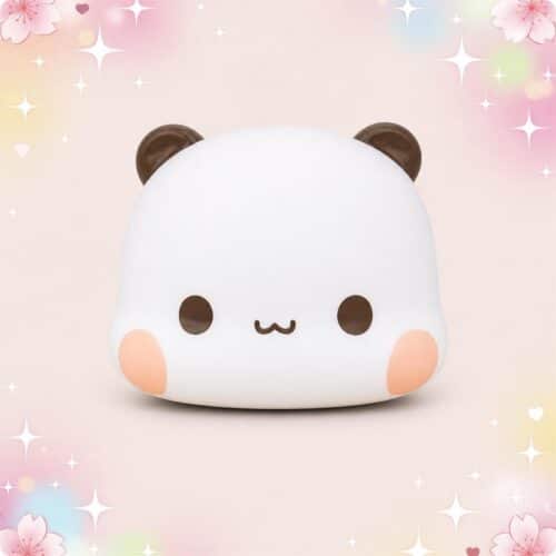 Un mochi squishy Bubu panda joufflu blanc avec des oreilles brunes et des joues roses, présenté sur un fond pastel décoré de fleurs et d’étoiles.
