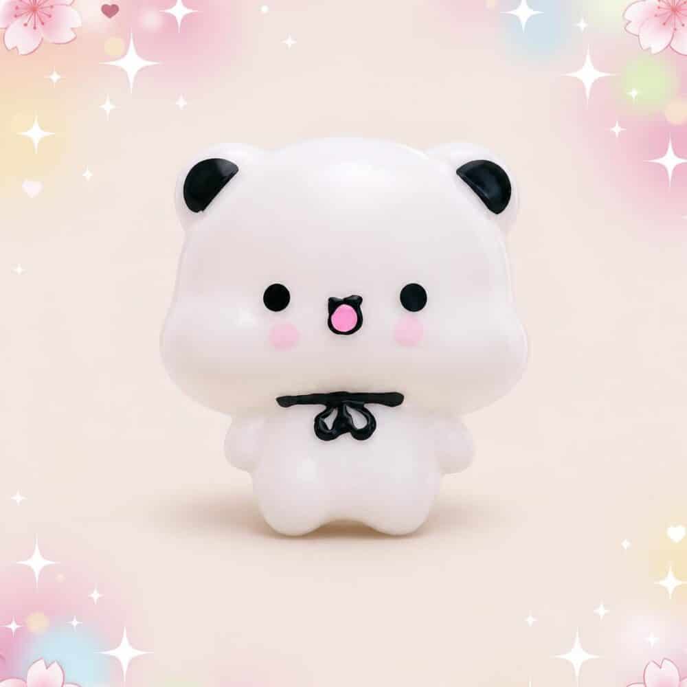 Un mochi squishy Bubu blanc avec un nœud papillon noir, issu du lot de 2 mochi squishies Bubu au nœud papillon, sur un fond rose décoré de fleurs et d’étoiles.