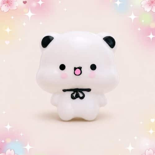 Un mochi squishy Bubu blanc avec un nœud papillon noir, issu du lot de 2 mochi squishies Bubu au nœud papillon, sur un fond rose décoré de fleurs et d’étoiles.