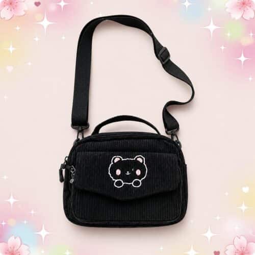 Un sac kawaii ours brodé sur velours côtelé noir, avec une bandoulière réglable et une petite poignée, présenté sur un fond pastel décoré de fleurs et d’étoiles.