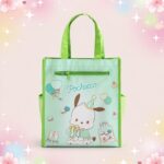 Un sac Kawaii tote bag imprimé Pochacco pour toutes occasions, vert clair, avec deux anses, une poche zippée et un dessin de Pochacco, posé sur un fond pastel décoré de fleurs et d’étoiles.