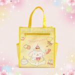 Un sac kawaii tote bag avec motif Pompompurin jaune, orné d’un personnage et de dessins de fête, présenté sur un fond pastel décoré de fleurs et d’étoiles.