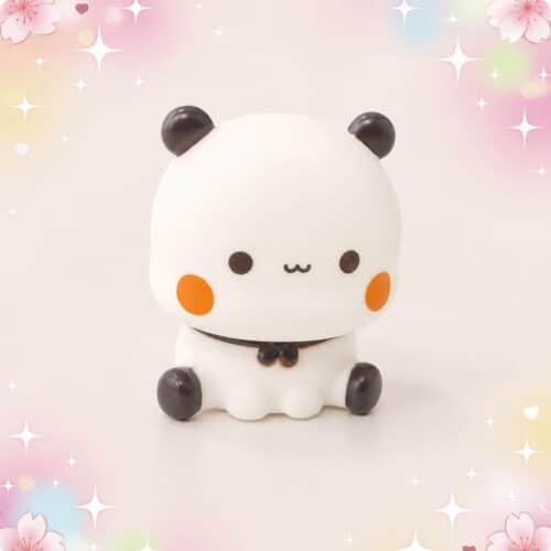 Une veilleuse Kawaii Bubu assis aux joues orange, représentant un petit personnage blanc assis avec des oreilles et des pieds noirs, sur un fond pastel décoré de fleurs et d’étoiles.