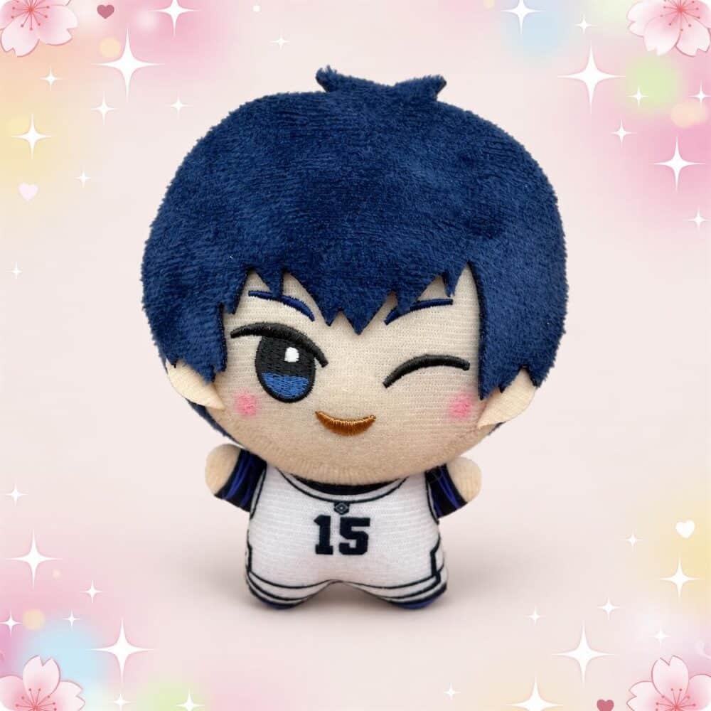 Un porte-clés peluche Isagi de Blue Lock en forme de petit personnage aux cheveux bleus, portant un maillot blanc marqué du numéro 15, posé sur un fond rose décoré de fleurs et d’étoiles.
