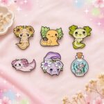 Un lot pins Kawaii axolotl et petites créatures marines, représentant six personnages adorables et colorés, disposés sur un fond rose décoré de fleurs et d’étoiles.